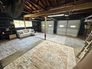 A spacious garage with a white sofa, patterned rugs, and a ceiling fan.