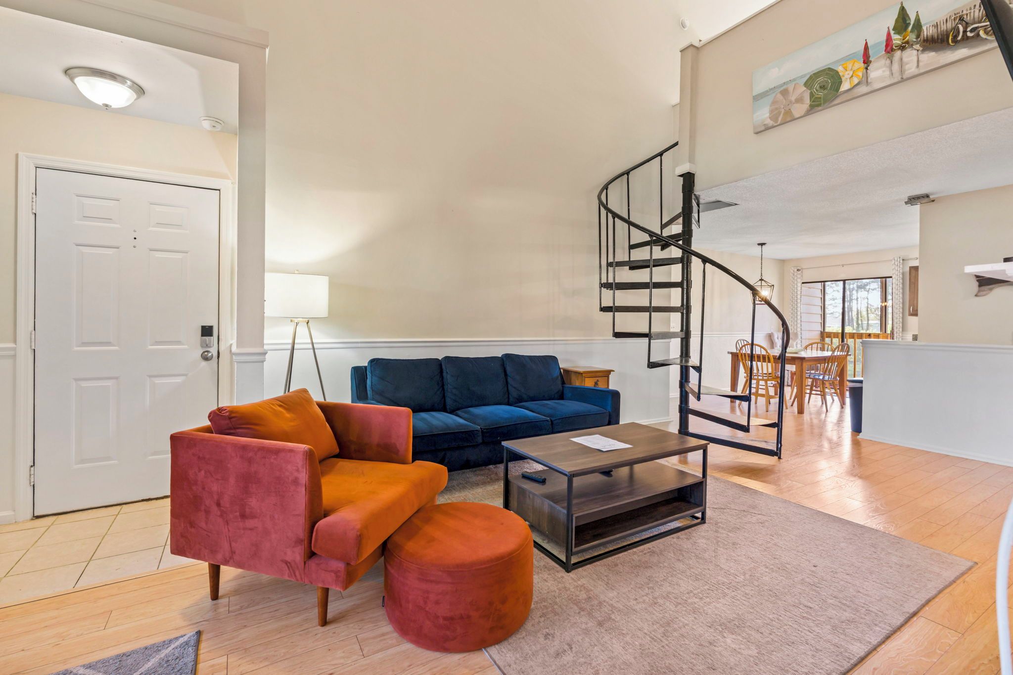 Una sala de estar con sofá, reposapiés, mesa de centro y una escalera en espiral.