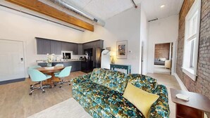 A modern living room with a sofa, chairs, a dining table, and a kitchen in the background.