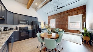 A modern kitchen with dark cabinets, a large stove, and a dining area with a round table and light blue chairs.