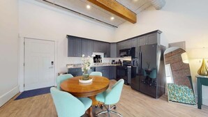A modern kitchen with grey cabinets, a wooden dining table, and a blue rug.