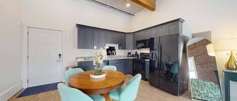 A modern kitchen with grey cabinets, a wooden dining table, and a blue rug.