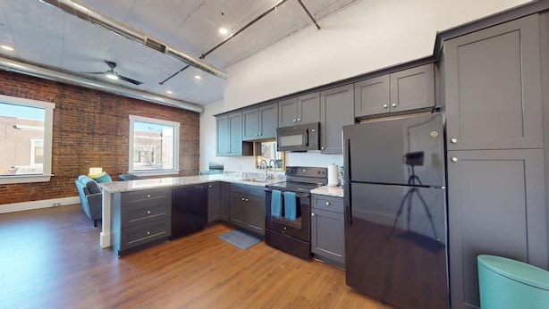 Una cocina moderna con armarios oscuros, una isla central y un refrigerador grande.
