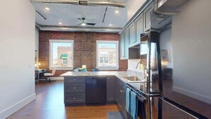 Una cocina moderna con armarios oscuros, un refrigerador de acero inoxidable y una isla grande.