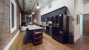 Una cocina moderna con armarios oscuros, una isla grande y un refrigerador empotrado.
