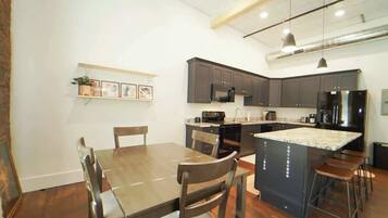 Una cocina moderna con gabinetes oscuros, una isla central y taburetes de bar.