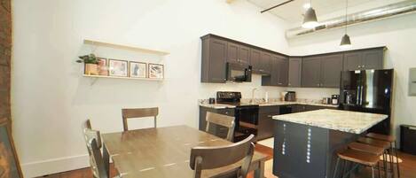 A modern kitchen with dark cabinets, a central island, and bar stools.