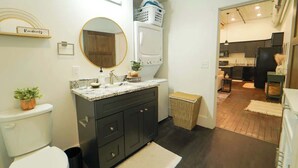 Ein modernes Badezimmer mit Toilette, Waschbecken und Spiegel. Eine Wäschekorb ist an der Wand und ein Korb auf dem Boden vorhanden.