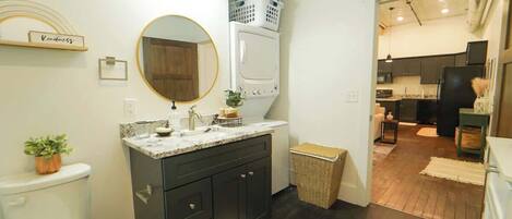 A modern bathroom with a toilet, sink, and mirror. There is a laundry basket on the wall and a wicker basket on the floor.