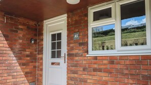 Fachada de ladrillo con una puerta blanca y una ventana.