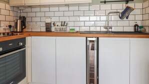 Una cocina moderna con armarios blancos, una estufa de acero inoxidable, un lavavajillas Bosch y un salpicadero de azulejos.