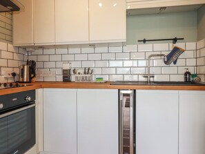 A modern kitchen with white cabinets, a stainless steel range, a Bosch dishwasher, and a tiled backsplash. - Fistral Bay Apt (Newquay)