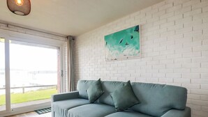 Una sala moderna con un sofá azul claro, una pared de ladrillo blanco y un cuadro con peces.
