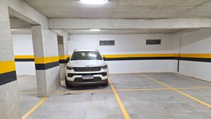 A white SUV parked in a concrete parking garage with yellow and black striped walls. - LK Centro 2 (Belo Horizonte)