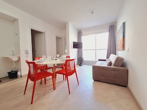 Una sala moderna con comedor, un sofá y una televisión.