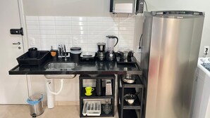 A compact kitchen with a black countertop, a stainless steel refrigerator, a microwave, and a sink. - LK Centro 2 (Belo Horizonte)