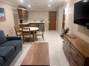A modern living room with a sofa, a coffee table, a TV, and a dining area with a table and chairs.