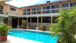 A hotel with a swimming pool, outdoor seating, and a covered balcony area. - Paria Suites Hotel and Conference Center (La Romain)