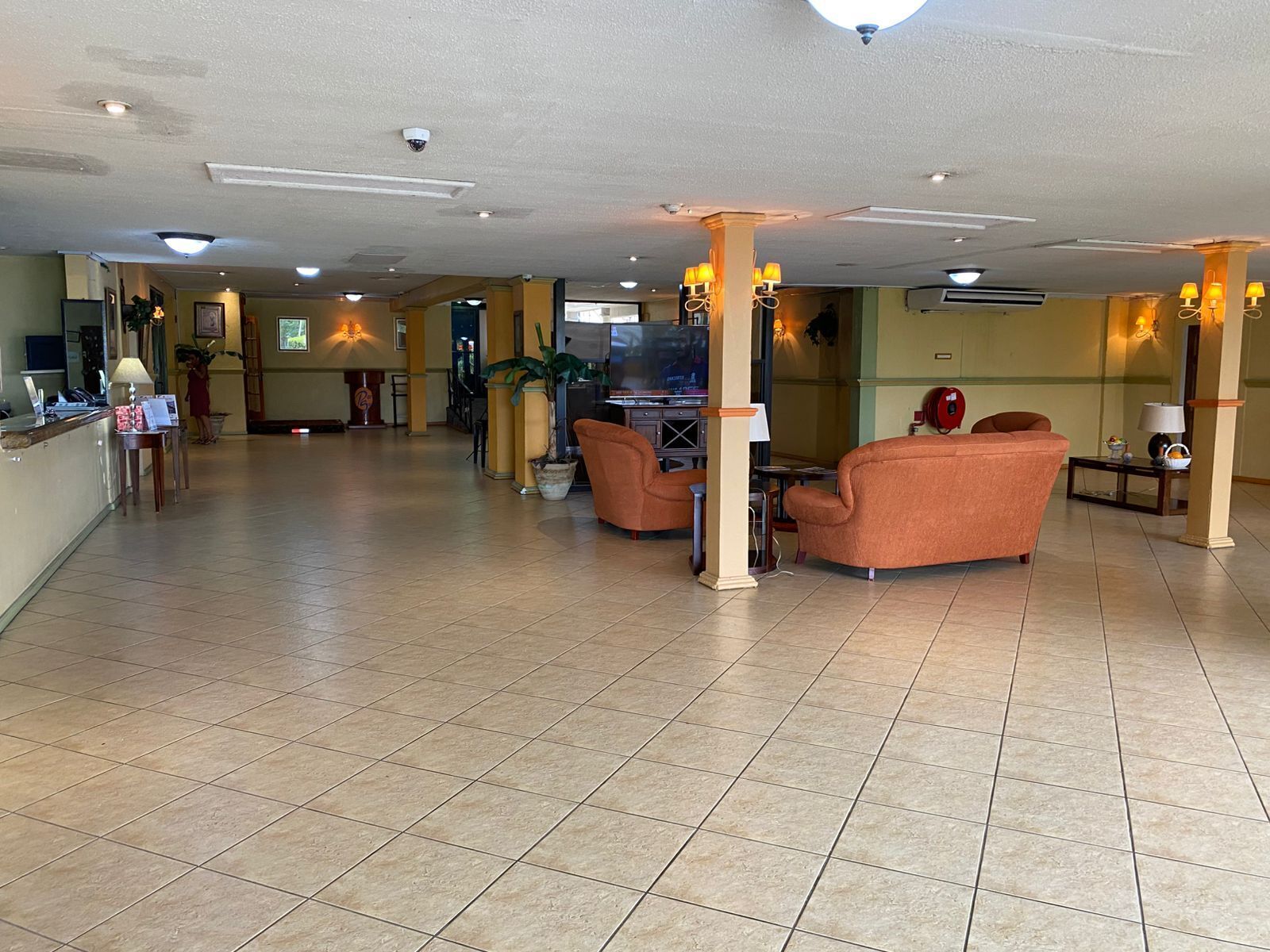 A spacious lobby with a reception desk, seating area, and a television.