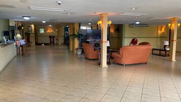 A spacious lobby with a reception desk, seating area, and a television.