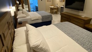 A hotel room with two beds, a TV, a desk, and a bathroom visible through an open door. - Paria Suites Hotel and Conference Center (La Romain)