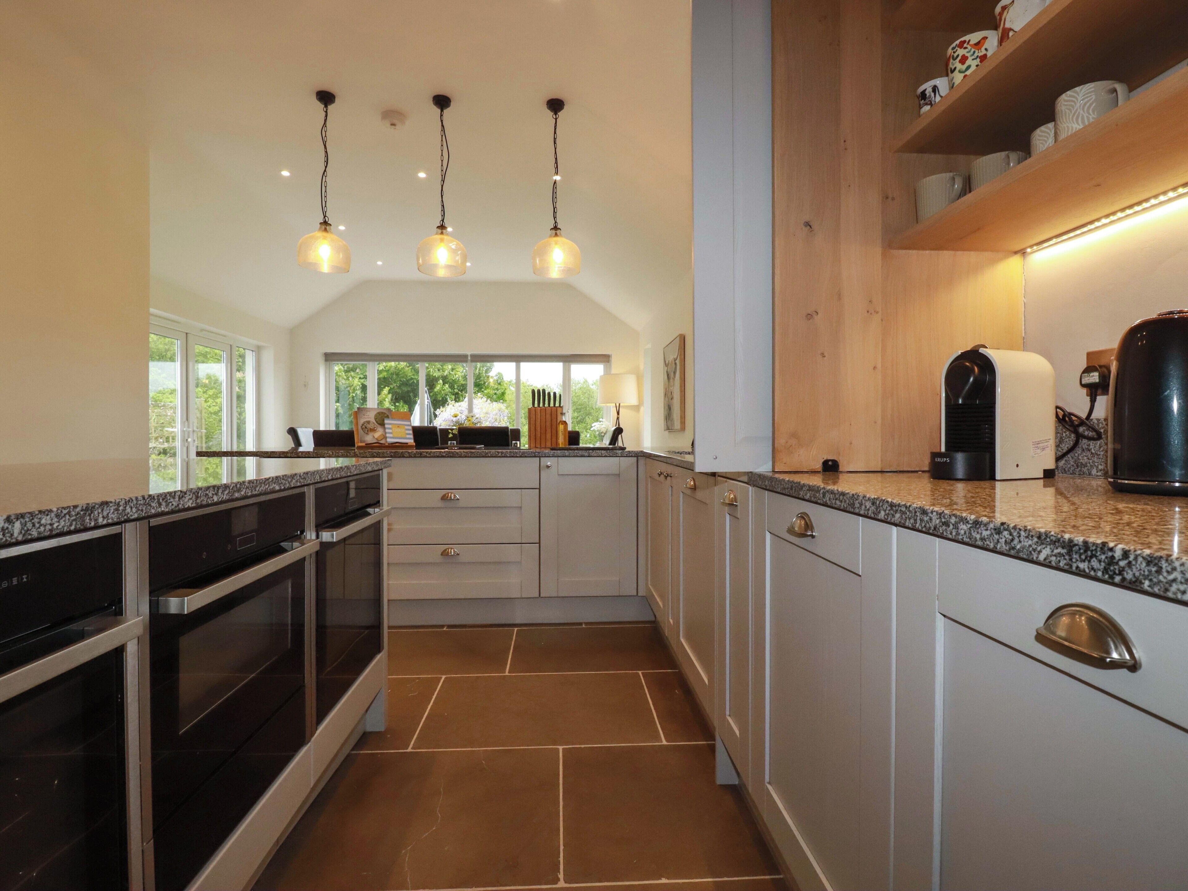 Una cocina moderna con encimeras de granito, electrodomésticos de acero inoxidable e iluminación colgante.