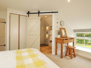 Ein Schlafzimmer mit Bett, einem Holztisch, einem Spiegel und einem Fenster mit Aussicht.
