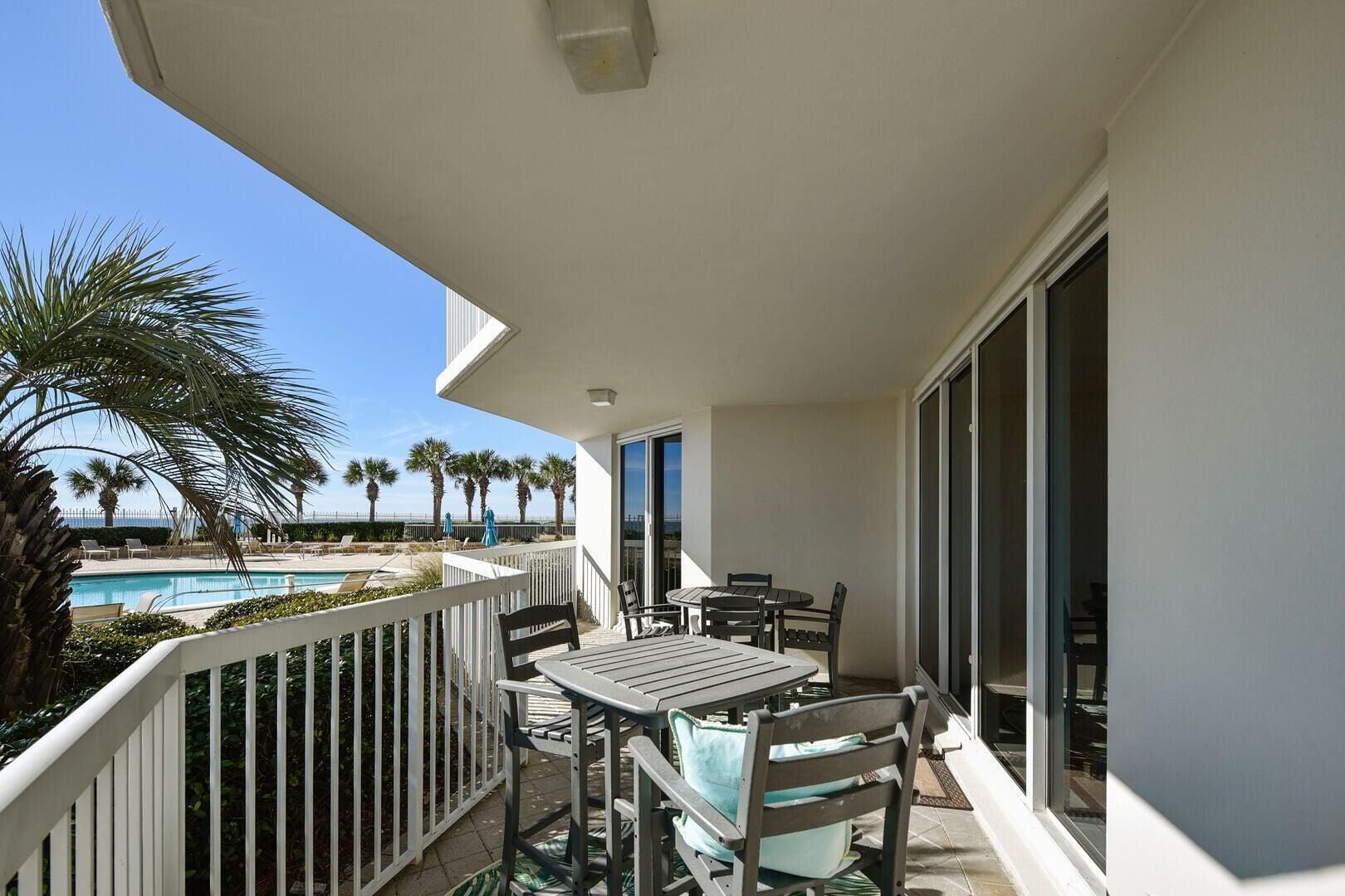 A balcony with a pool, chairs, and a table.