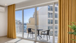Ein Balkon mit Glastür, zwei Stühlen und einem Blumentopf.