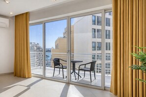 Ein Balkon mit Glastür, zwei Stühlen und einem Blumentopf.