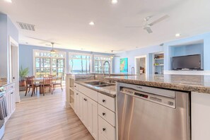 Een moderne keuken met een vaatwasser, een eethoek met stoelen en een tv op een standaard.