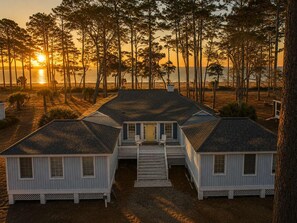 Een strandhuis met een hoofdgebouw en twee gastenverblijven, verbonden door een overdekte gang.