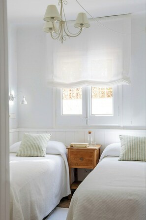 Ein Schlafzimmer mit zwei Betten, einem Chandelier, einem Fenster mit Blick und einem Nachttisch aus Holz.