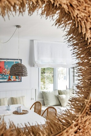 Ein Zimmer mit Esstisch, Stühlen, einer Hängeleuchte, einem Fenster mit Aussicht und einer wandmontierten Klimaanlage.