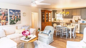 A living room with a sofa, armchair, and a dining table with chairs. There is a kitchen area with cabinets and a microwave. - Stylish Waterfront Retreat in Bayview-Boat Dock (Bayview)