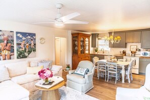 A living room with a sofa, armchair, and a dining table with chairs. There is a kitchen area with cabinets and a microwave. - Stylish Waterfront Retreat in Bayview-Boat Dock (Bayview)