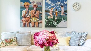 A living room with a sofa, pillows, a vase of flowers, and two paintings on the wall. - Stylish Waterfront Retreat in Bayview-Boat Dock (Bayview)