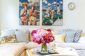 A living room with a sofa, pillows, a vase of flowers, and two paintings on the wall. - Stylish Waterfront Retreat in Bayview-Boat Dock (Bayview)
