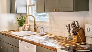A kitchen with a wooden countertop, a double sink, a potted plant, a knife block, and a dishwasher. - Stylish Waterfront Retreat in Bayview-Boat Dock (Bayview)