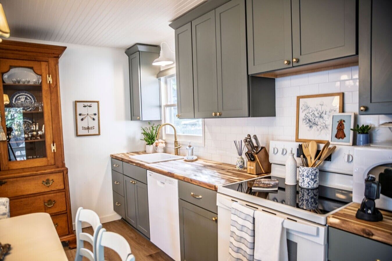 A kitchen with grey cabinets, a wooden countertop, a sink, and a stove.