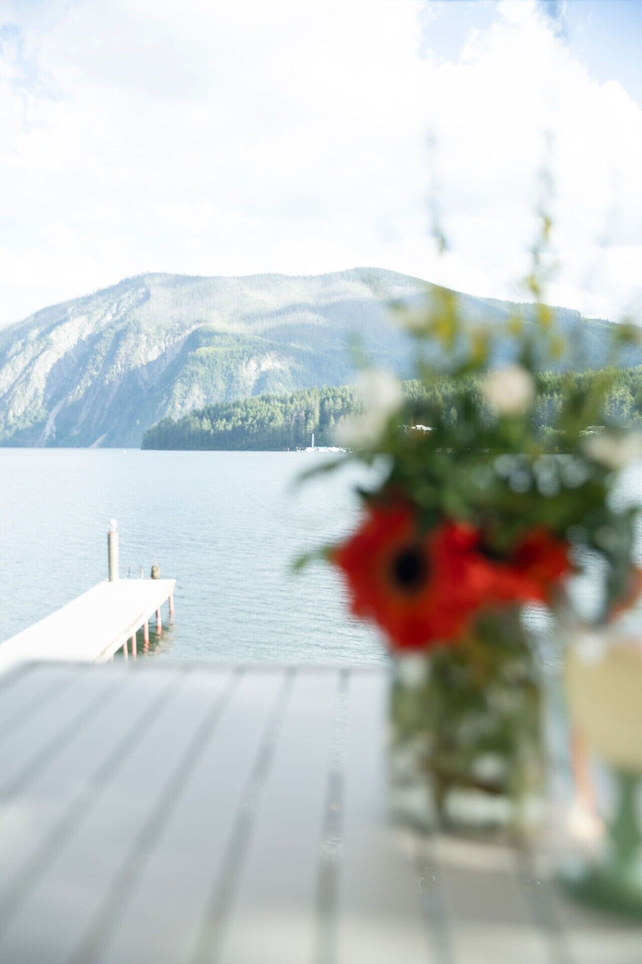 A lake with a dock extending into it, surrounded by mountains.