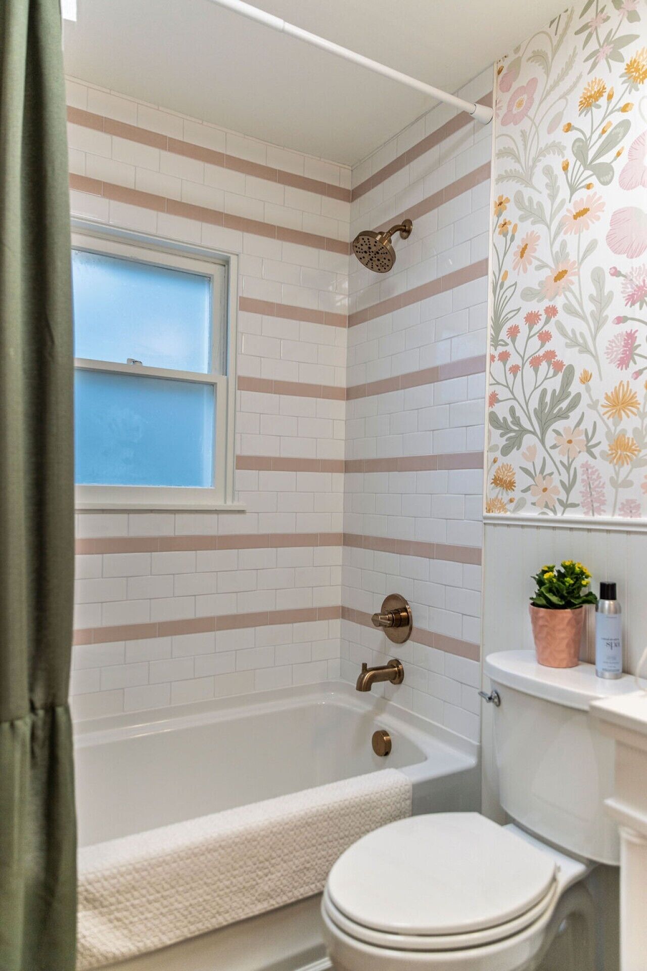 Een badkamer met een bad, toilet en raam.