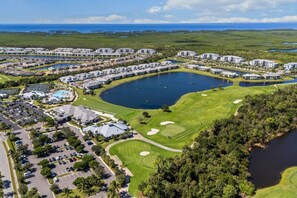 Ein Golfplatz mit einem großen See, umgeben von Wohngebäuden und einem Parkplatz.