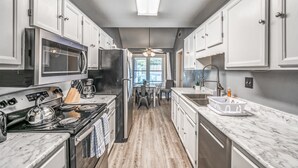 A modern kitchen with white cabinets, a built-in oven, a microwave, and a sink. - Fenced Yard w/ Pool! Comfy & Convenient in Cordova (Memphis)