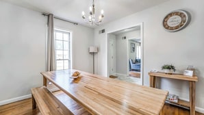 Una habitació àmplia amb taula de dinar de fusta, una banca, un penjador i un rellotge a la paret.
