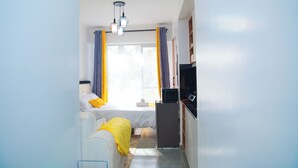 A bedroom with a bed, a desk, a chair, a television, and a window with curtains. - Charming apartment in pleasant Kiambu perfect for your getaway (Kiambu)