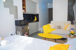 Ein Hotelzimmer mit Bett, einer Couch, einer kleinen Küchenzeile und einem Esstisch.