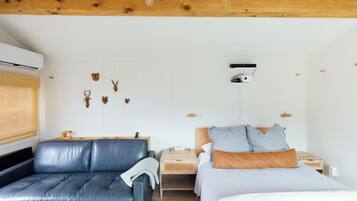A bedroom with a bed, a sofa, a nightstand, and wall-mounted decor.