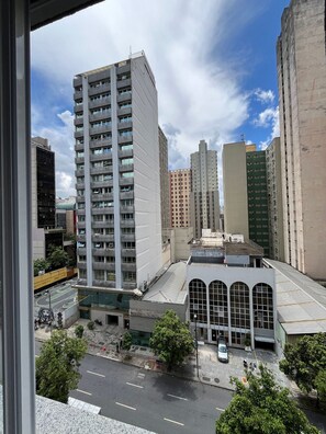 Un edificio de gran altura con varios pisos, un estacionamiento y una calle arbolada.