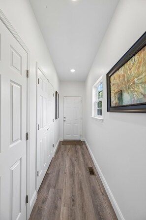 A hallway with white doors, a wooden floor, and a framed painting on the wall. - Lookout Retreat  Near Chattanooga (Trenton)